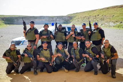 Group shot of cadets in bulletproof vests armed with M16 assault rifles against a background of a special forces vehicle, training center, Israel
